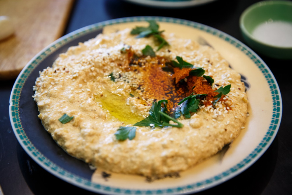 Lentil hummus in bowl and pita bread on wooden table