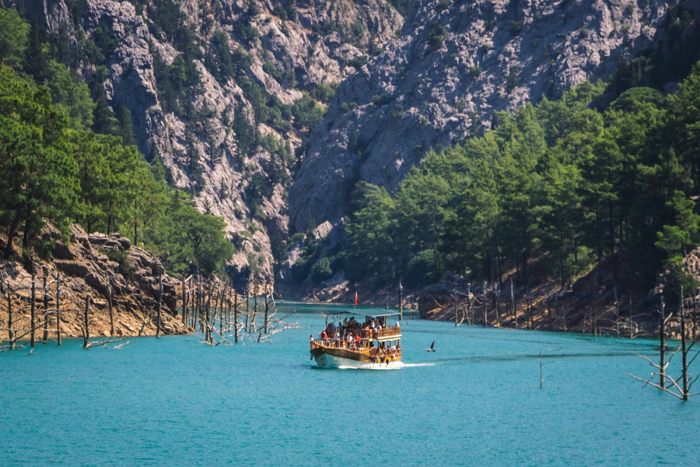 Деревянный туристический катер плывет в зеленом каньоне Аланьи в Турции